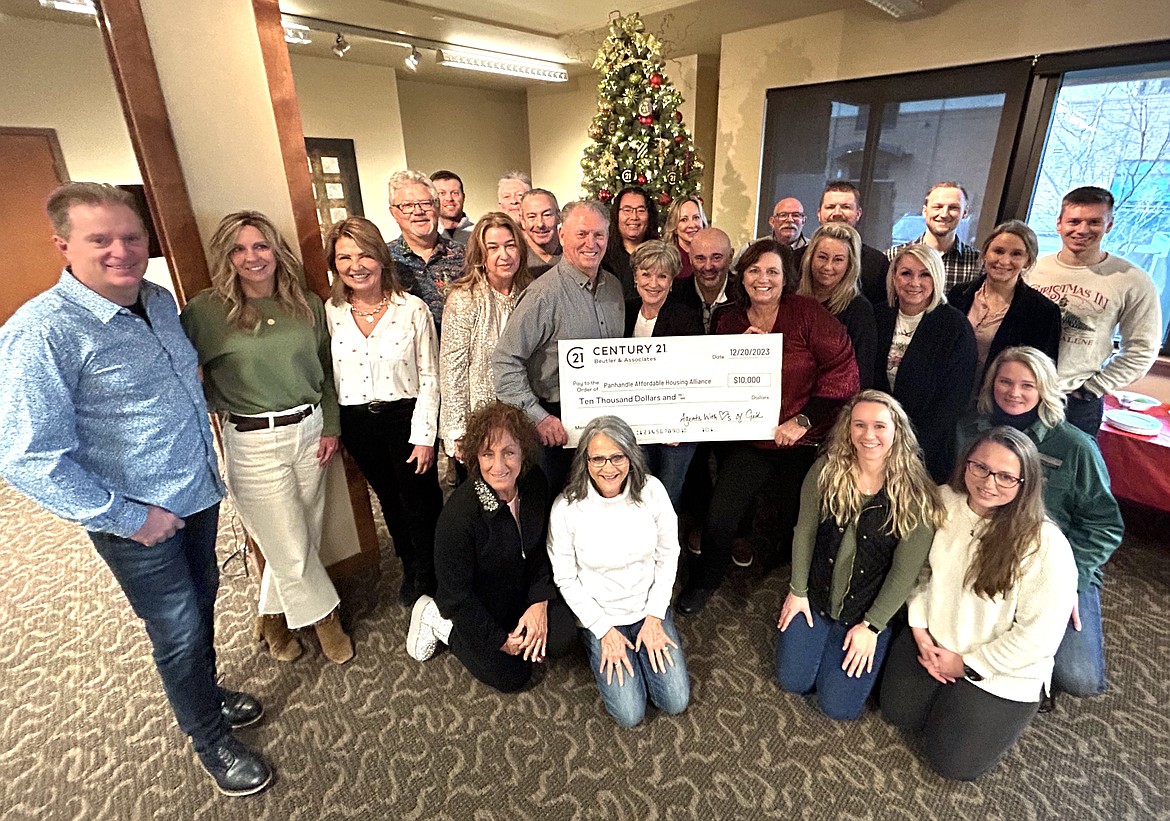 Century 21 Beutler and Associates with the "Agents With Hearts of Gold" program donate $10,000 to the Panhandle Affordable Housing Alliance on Wednesday. Kneeling are Kristen Johnson, Brenda Hauck, Beca Odenthal, Brittany Cowan and Shawna Daniels.Standing front row: Rob Elder, Anne Sumner, Ann Beutler, Kellie Hanna, John Beutler, Maggie Lyons of PAHA, Franco DeSimone, Christine Matheny, Leslie Langley, Karen Erickson and Danielle Kuntz. Standing back row: Steve Mumm, Walt Wardak, Kosh Shioya, Suzan Mascall, Roland Mueller, Tommy Beutler, Marcus Butler and Miles Pointer. Standing in the far back to the left of the tree are Travis Leavitt and Gary Schultz.