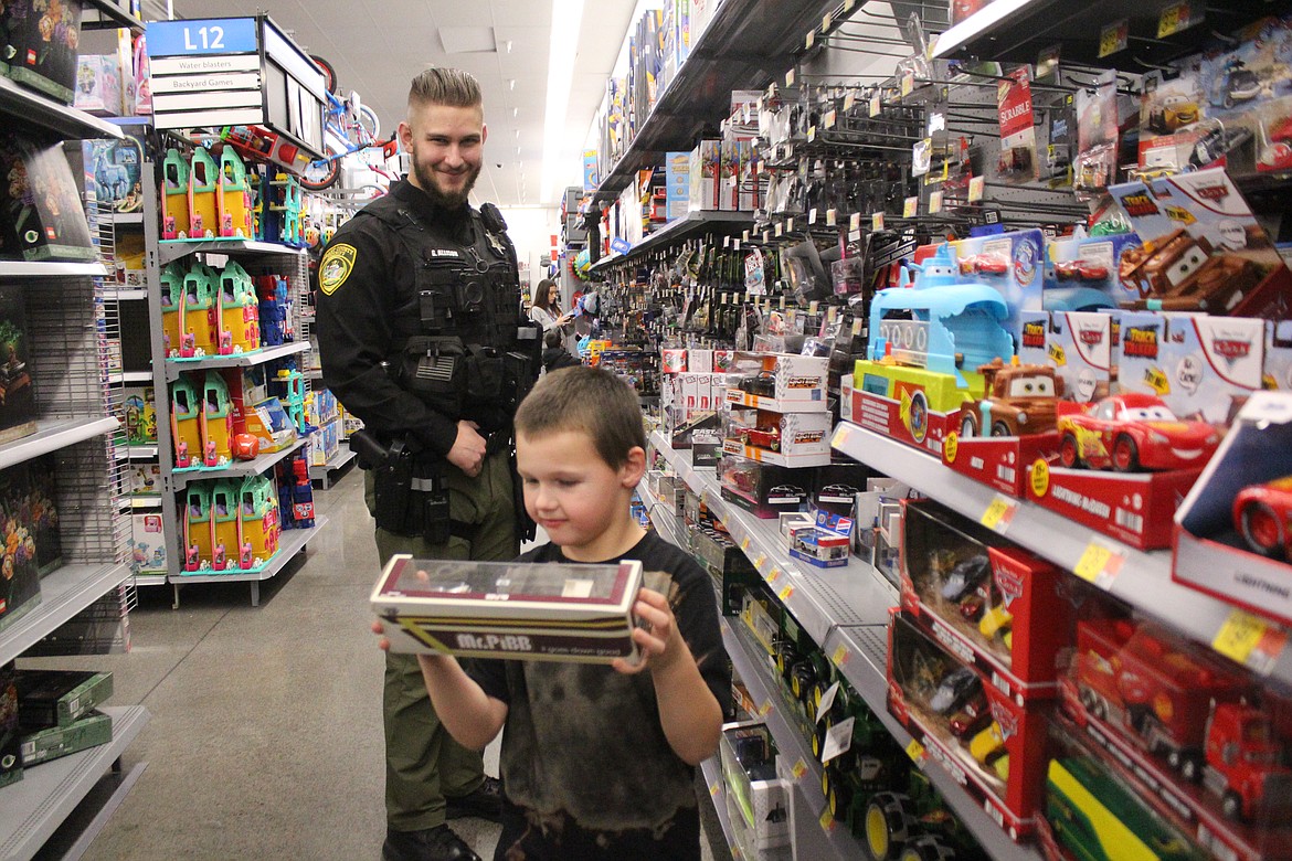 Grant County Sheriff’s Office Deputy Gaven Allison, back, and his shopping buddy Maxtin, front, found just the right gift in the toy aisle during Shop With a Cop Tuesday.