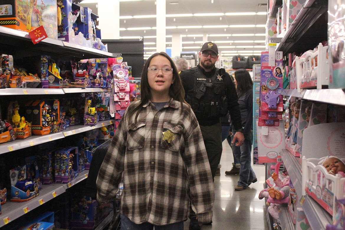 Grant County Sheriff’s Deputy Stormy Baughman, rear, and his shopping buddy Lakota weigh the merits of the toy options during Shop With a Cop Tuesday.