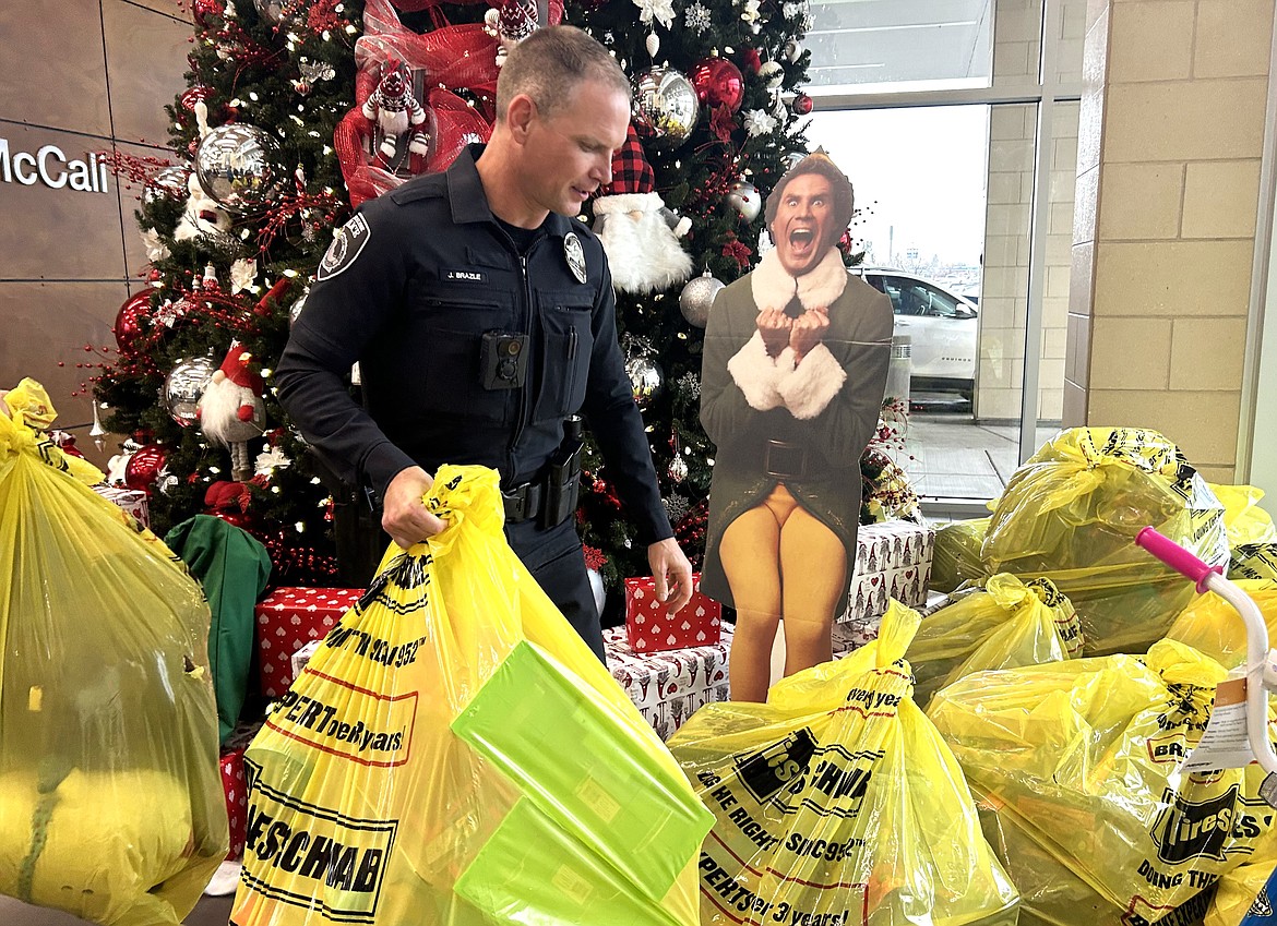 Jake Brazle of the Coeur d'Alene Police Department carries a bag of toys into Kootenai Health on Wednesday.