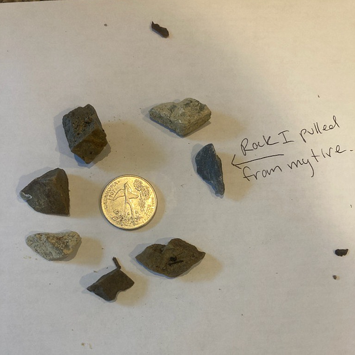 Anthony Banker put the rock was removed from his vehicle's tire and some of the gravel on the road next to a quarter for comparison.