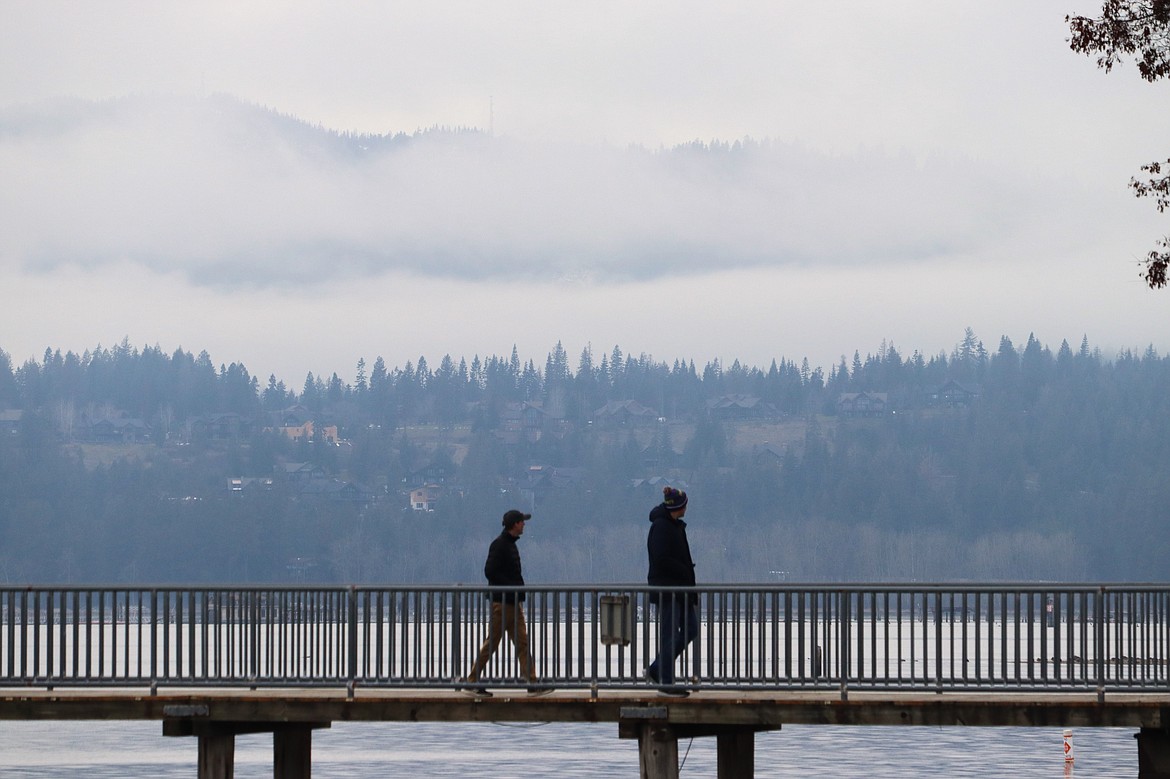 Clouds settled over the mountains across Lake Coeur d'Alene while two people walk from the dock at Independence Point on Thursday.