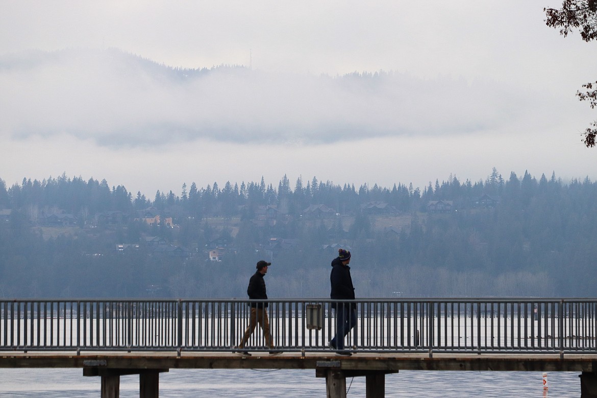 Clouds settled over the mountains while two people walk from the dock at Independence Point on Thursday.