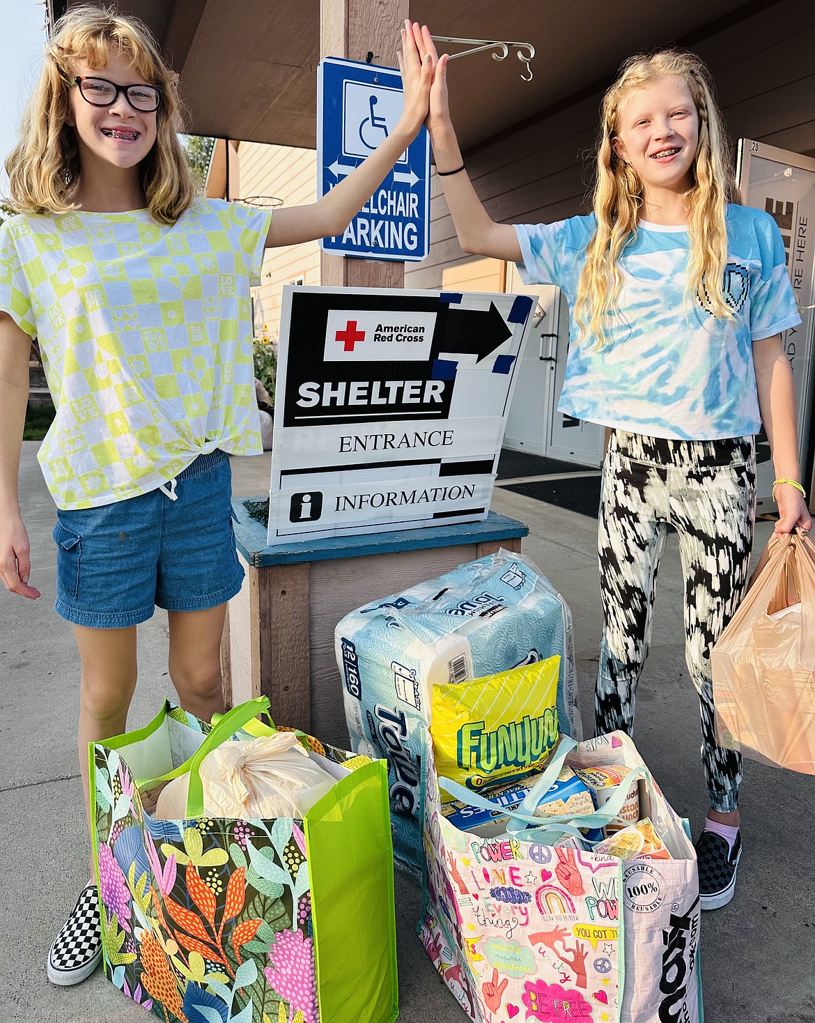 Penelope White (left) high fives Olivia White during a drop off of donations to Sanders county residents back during the River Road East Fire in August. (Photo courtesy/AnnaMarie Guerra-White)