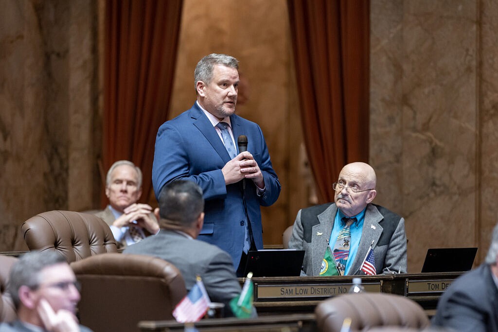 Local State Representative Tom Dent, R-Moses Lake, seated behind flags, looks on as State Representative Sam Low, R-Lake Stevens, standing, speaks during a prior legislative session in Olympia. Low has submitted a bill for consideration that aims to help protect Washingtonians from second-hand exposure to fentanyl and other narcotics.