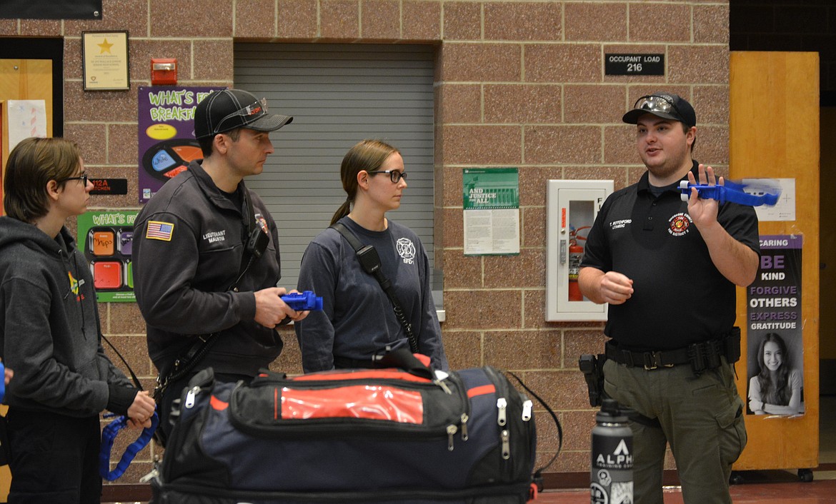 Kadie Corwin, Victor Malsom, and Ashley Christmann listen as Tyler Rotchford of Shoshone Fire District No. 2 details best practices in the application of a tourniquet for a patient with bodily trauma.