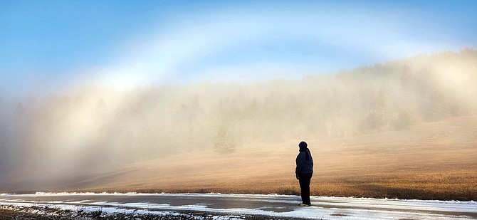 A woman stops to admire a rainbow that seemed to rise from the fog at a Kootenai County farm in this 2023 file photo.