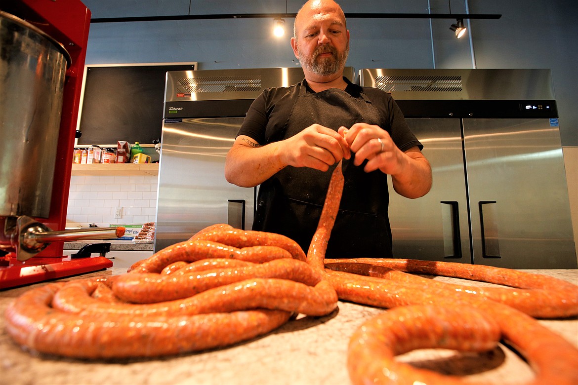 Ben Drake works on a coil of sausage Gentleman Sausages that opened on Fourth Street in downtown Coeur d’Alene in 2023.