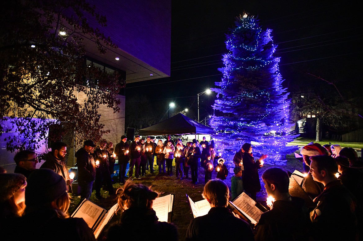 Attendees gather and hold candles while members of the Flathead High School Choir sing at the Christmas Blue Light Tree Lighting ceremony outside the Flathead County Justice Center in Kalispell on Thursday, Dec. 7. The event is held to support the families of fallen officers and to honor the officers, highway patrol, firefighters, first responders and all those who serve and protect. (Casey Kreider/Daily Inter Lake)