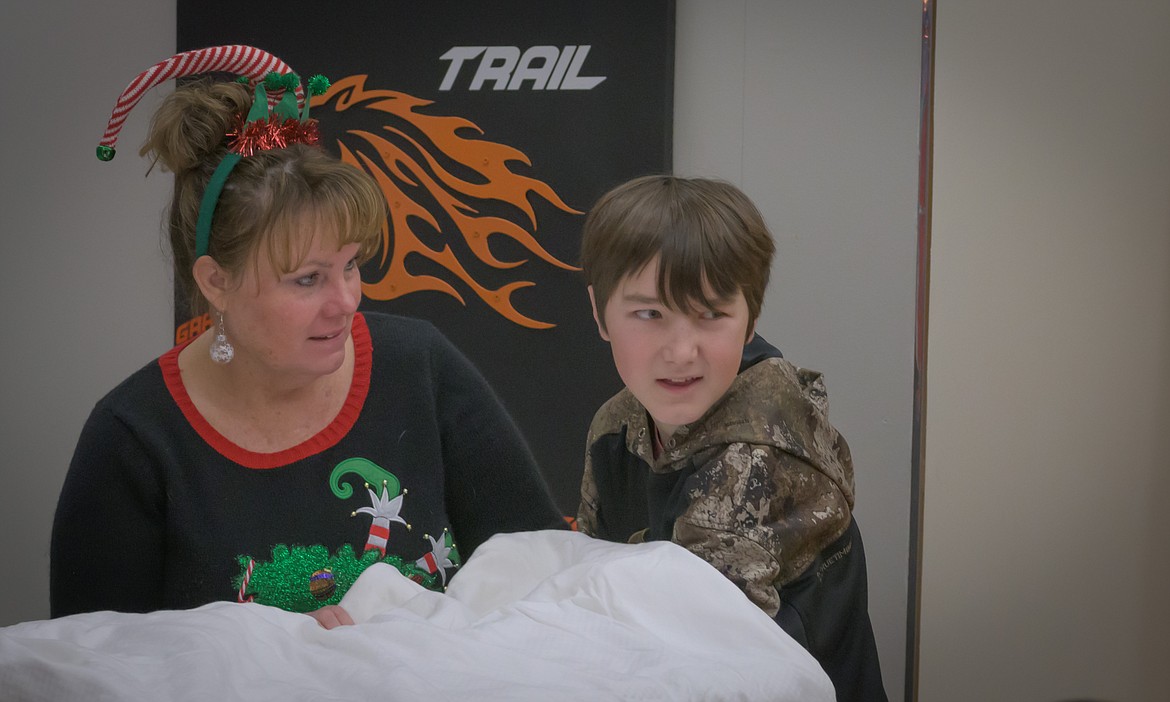 Art teacher Kristen Cole helps Bryon Lakko figure out what is the gift that is hiding in a box. (Tracy Scott/Valley Press)