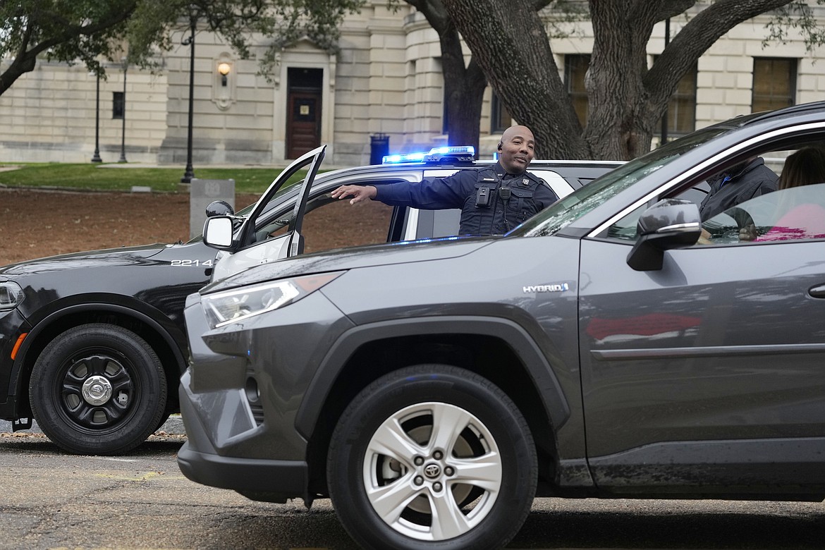 A Capitol Police officer directs traffic away from the Mississippi State Capitol as they respond to a bomb threat at the state house in Jackson, Miss., Wednesday morning, Jan. 3, 2024. The building was emptied, the grounds cleared of vehicles as officers investigated. (AP Photo/Rogelio V. Solis)