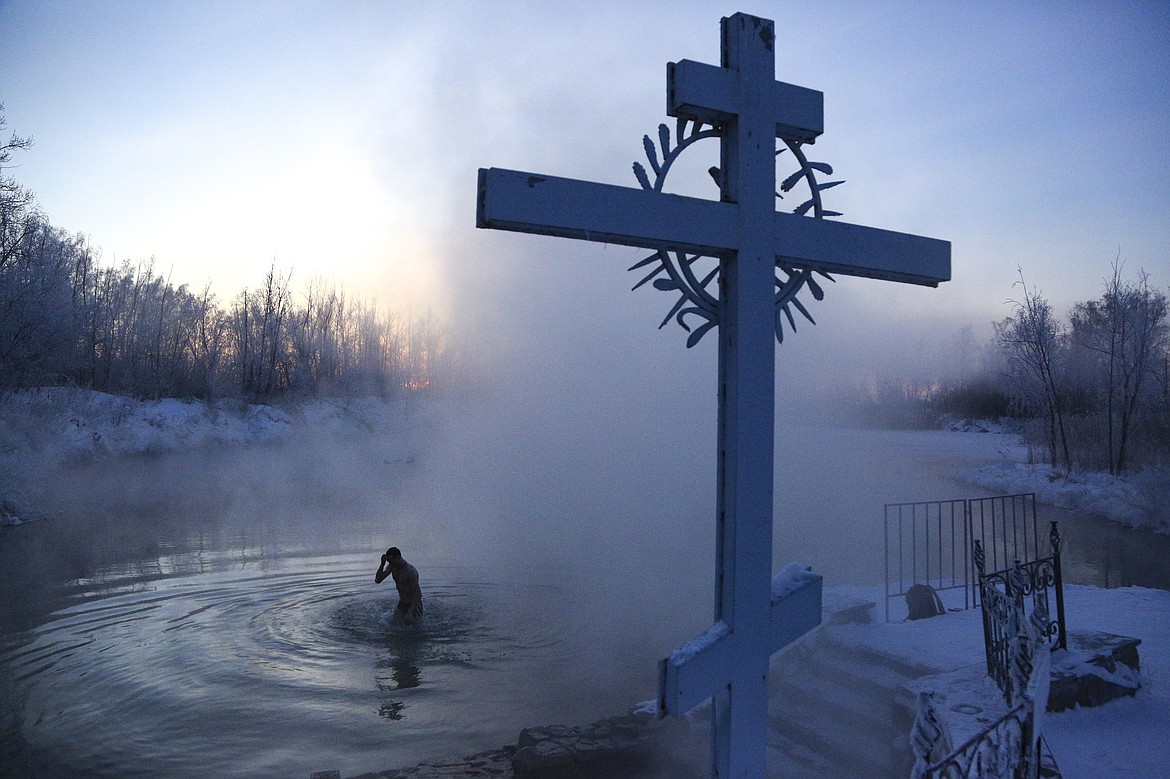 A man crosses himself while bathing in the water during a traditional Epiphany celebration as the temperature dropped to about -24 degrees (-11,2 degrees Fahrenheit) near the Achairsky monastery outside Siberian city of Omsk, Russia, Tuesday, Jan. 19, 2021. Water that is blessed by a cleric on Epiphany is considered holy and pure until next year's celebration, and is believed to have special powers of protection and healing. The Russian Orthodox Church follows the old Julian calendar.. (AP Photo/Evgeniy Sofiychuk, File)