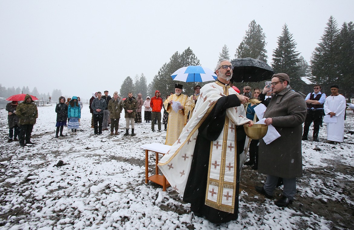 The Rev. Daniel Triant of Spokane's Holy Trinity Greek Orthodox Church scatters holy water onto the bowed heads of the faithful Saturday during a Theophany ceremony in Post Falls.