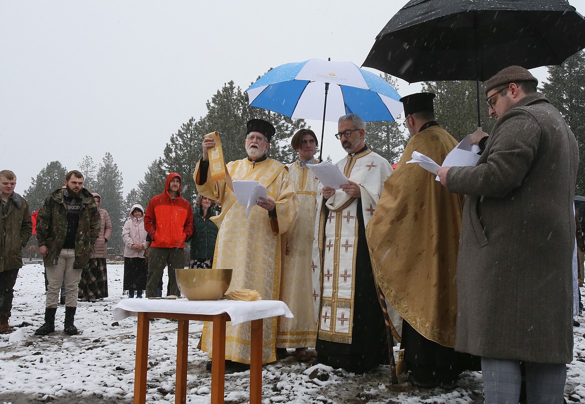 Deacon Joseph Mannion of St. John the Baptist Antiochian Orthodox Church lifts his stole as he says prayers to bless the waters Saturday during a Theophany ceremony on the Spokane River in Post Falls.