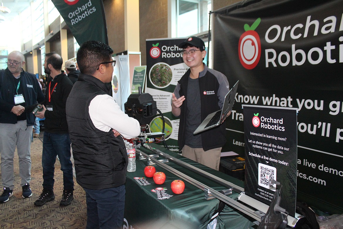 Charlie Wu, right, owner of Orchard Robotics, shows some of the options available from his company during the trade show that was part of the Washington State Tree Fruit Association annual meeting.