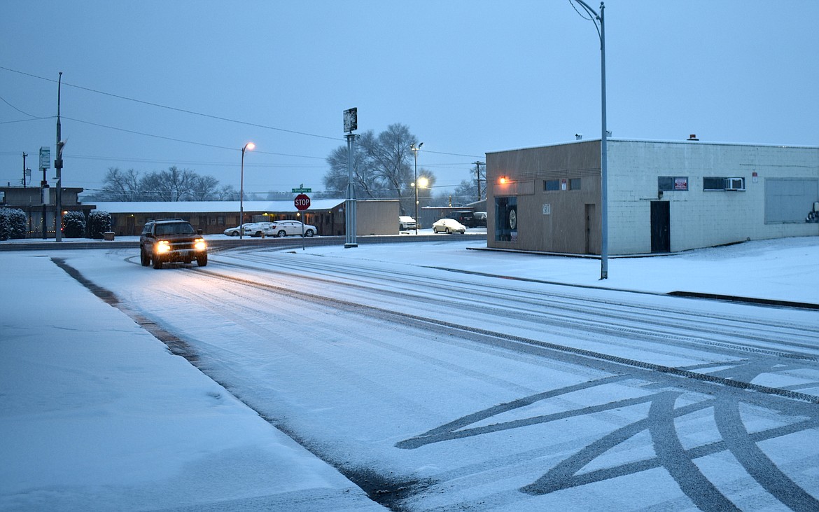 A pickup makes its way carefully down a snowy street in downtown Moses Lake Monday.