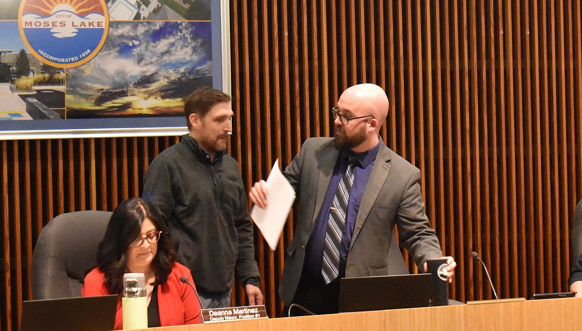 Newly-elected mayor Dustin Swartz, standing left, trades places with outgoing mayor and council member Don Myers at the Moses Lake City Council meeting Tuesday. Outgoing Deputy Mayor Deanna Martinez, seated, also exchanged seats with the new deputy mayor, Judy Madewell.