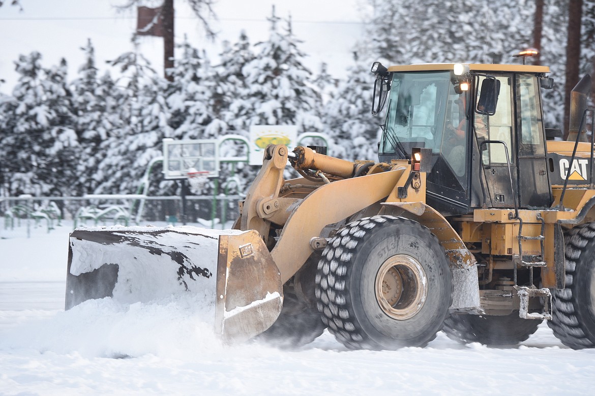 A heavy equipment operator plows snow in the parking lot at Libby Christian Church Friday morning. (Scott Shindledecker/The Western News)