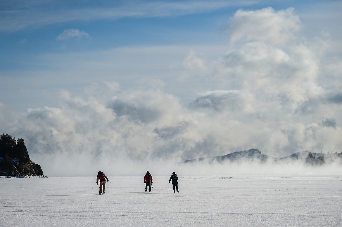 Ian Bartling and Beth and David Steele ice skate across the surface of Flathead Lake's Somers Bay as steam fog rises off the lake on Saturday, Jan. 13. (Casey Kreider/Daily Inter Lake)