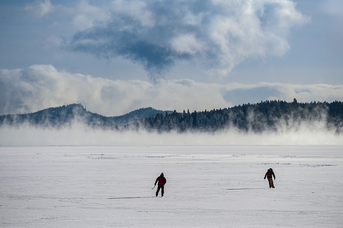 Ian Bartling and David Steele ice skate across the surface of Flathead Lake's Somers Bay as steam fog rises off the lake on Saturday, Jan. 13. (Casey Kreider/Daily Inter Lake)