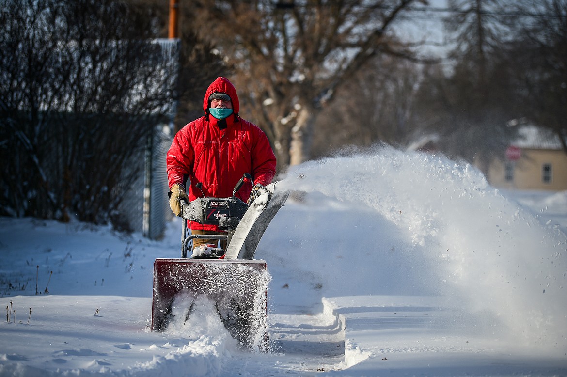 Jay Dundas uses a snowblower to clear snow from the sidewalks and garages around his neighbors' residences with the help of friend and neighbor Mary Anne Miller at Sixth Avenue West and and Fifth Street West in Kalispell on Friday, Jan. 12. (Casey Kreider/Daily Inter Lake)
