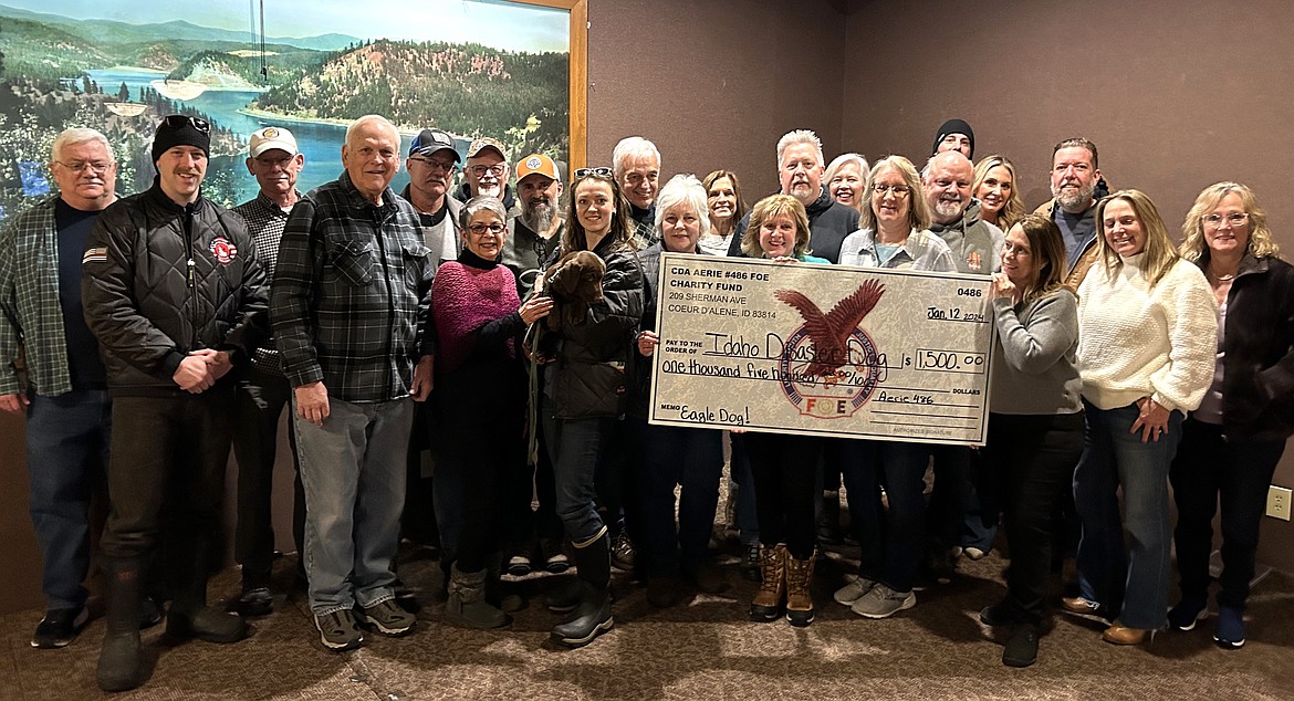 Members of the Coeur d'Alene Eagles gather for a picture with Morgan Zajicek and Eagle, the chocolate lab they bought for Idaho Disaster Dogs, at their Sherman Avenue club on Friday.
