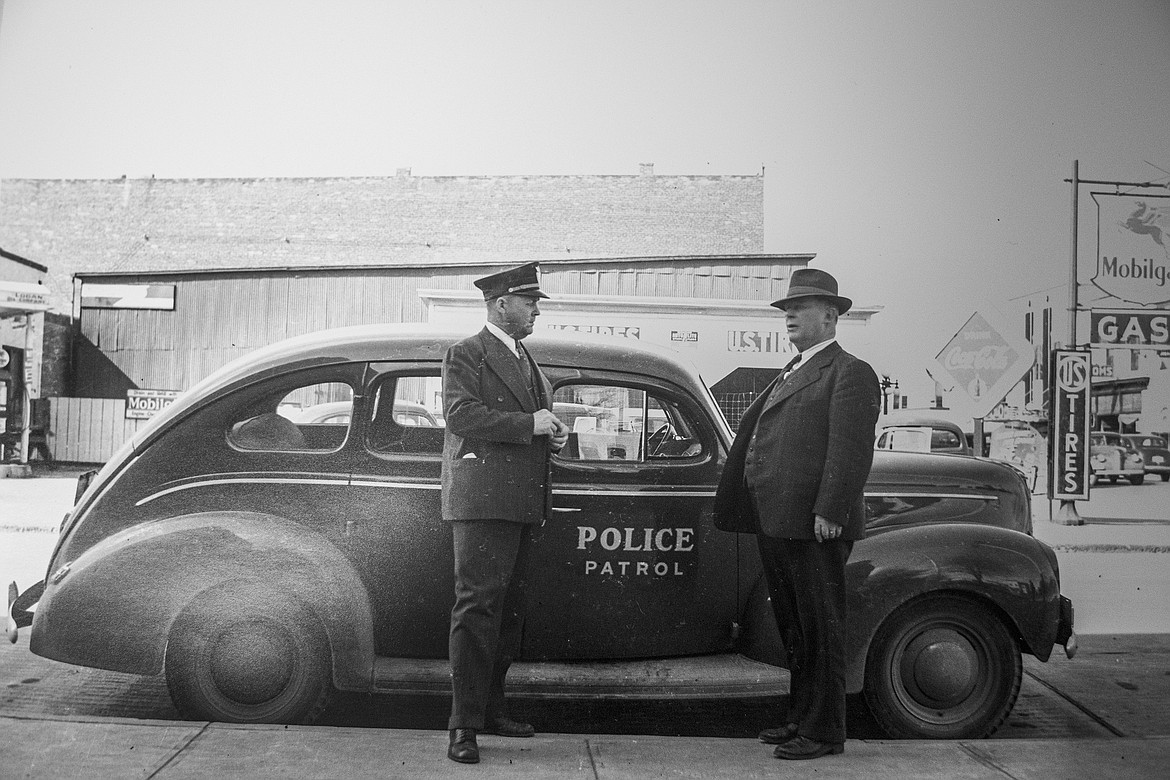 Kalispell Police officers stand by a patrol car on First Avenue East and Third Street (adjacent to police station and water department) in this photo by Raymond "Ray" Weaver. Weaver's photos, which depicted everyday life in a midcentury American town, will be on display at the Northwest Montana History Museum in Kalispell through the winter months. (Photo by Ray Weaver)