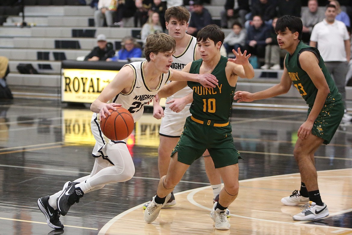 Royal senior Caden Allred, left, dribbles the ball toward the paint in the first half against Quincy Saturday.