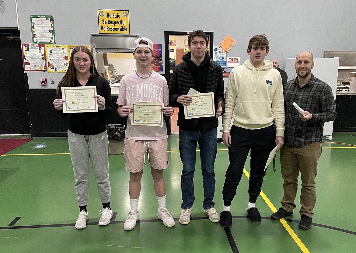 Jamie Kearby, Dillon Thomas, Jack Connolly, Kaden Sanders and history teacher Jeff Stanek show off the student's winnings from the first time attending the Montana Stock Market Game. (Photo courtesy St. Regis Schools)