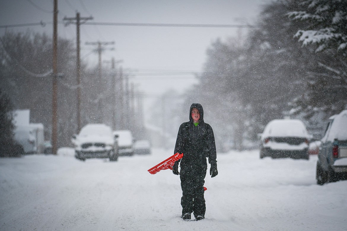 Dalen Wagner walks to a neighbor's residence to shovel their snow-covered sidewalks along Sixth Street West during a snowstorm Wednesday afternoon Jan. 17. (Casey Kreider/Daily Inter Lake)