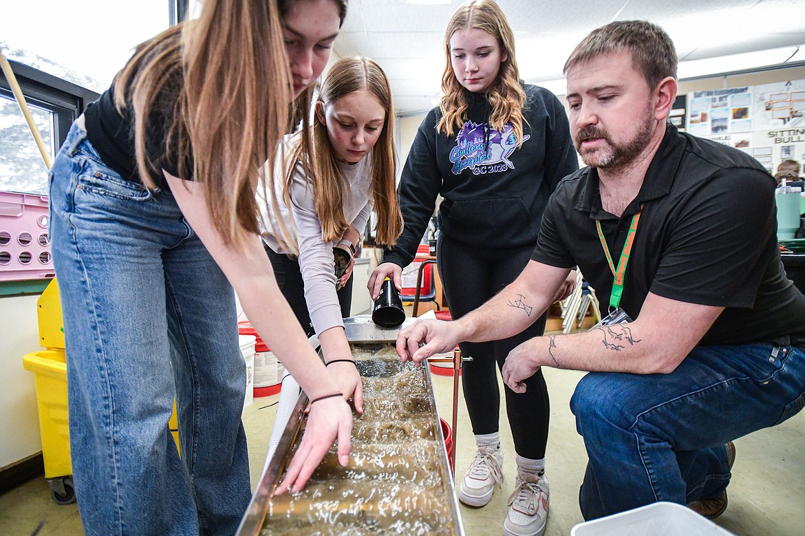 Kalispell Middle School teacher Kris Schreiner demonstrates how to use a sluice to eighth-graders, from left, Shyann Richsel, Hallie Granley and Kaylee Whitten during a lesson on panning for gold, garnets and other minerals in his Montana History class on Tuesday, Jan. 16. (Casey Kreider/Daily Inter Lake)