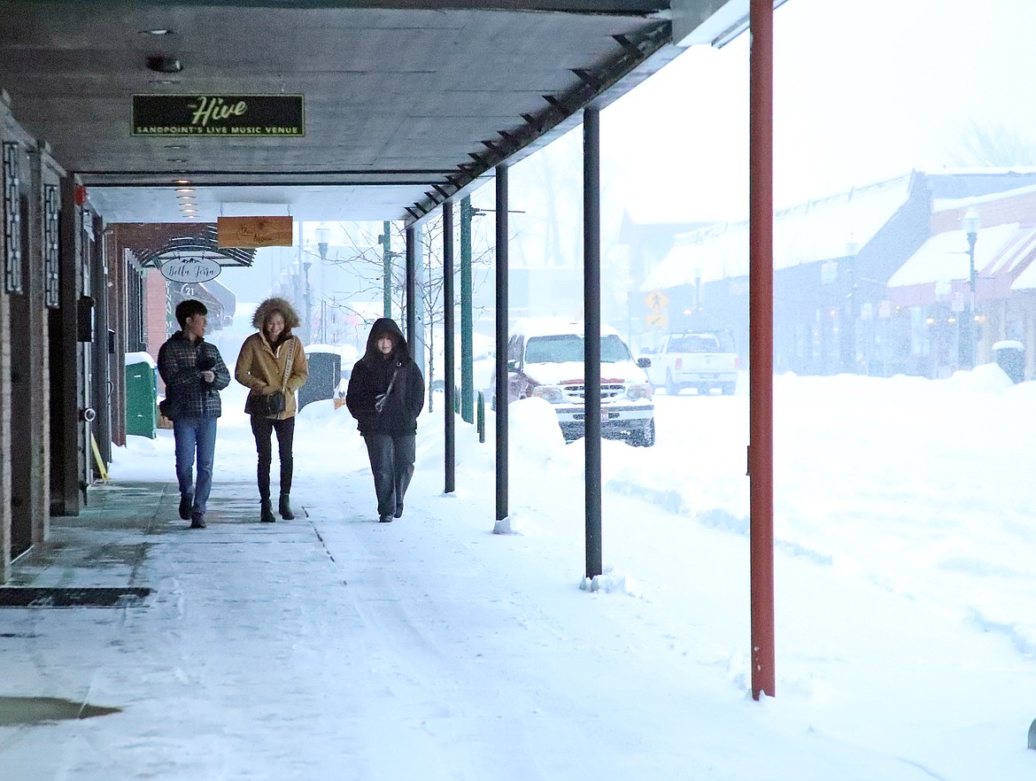 A trio walks along First Avenue mid-afternoon on Wednesday as a snowstorm blanketed the region throughout the day.