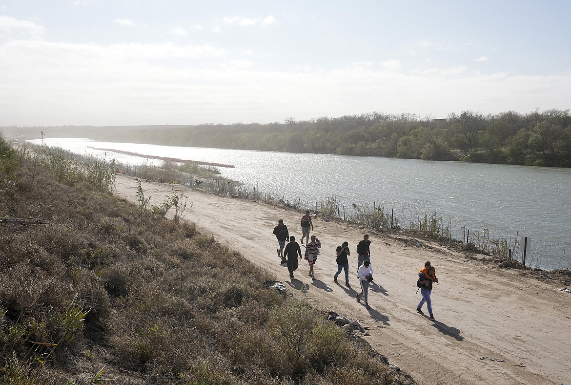 A group of migrants from Venezuela walk along the banks of the Rio Grande to surrender to U.S. Border Patrol after they entered Eagle Pass, Texas, Monday, Jan. 8, 2024. (Jay Janner/Austin American-Statesman via AP)