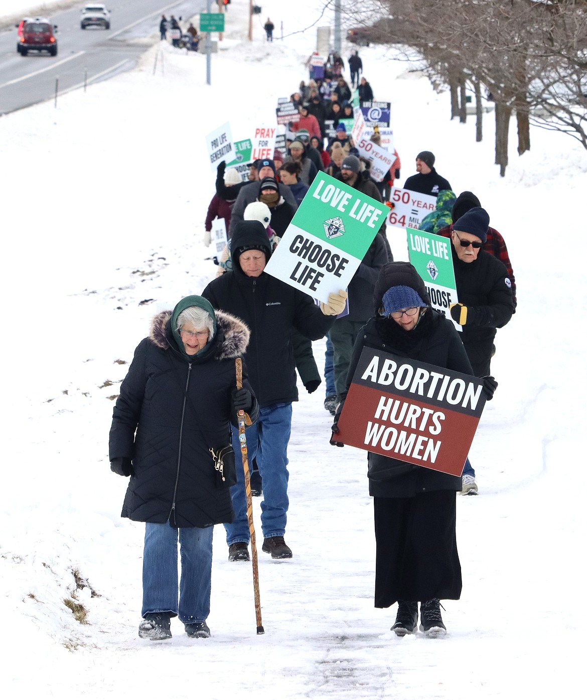Friends Sue Bockelman and Mary Walliser lead some of those who came out for the Right to Life Coeur d'Alene march Saturday next to U.S. 95.