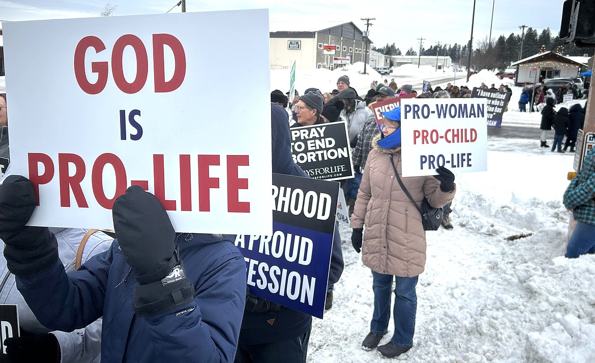 Pro-lifers hold signs as they cross U.S. 95 on Saturday.
