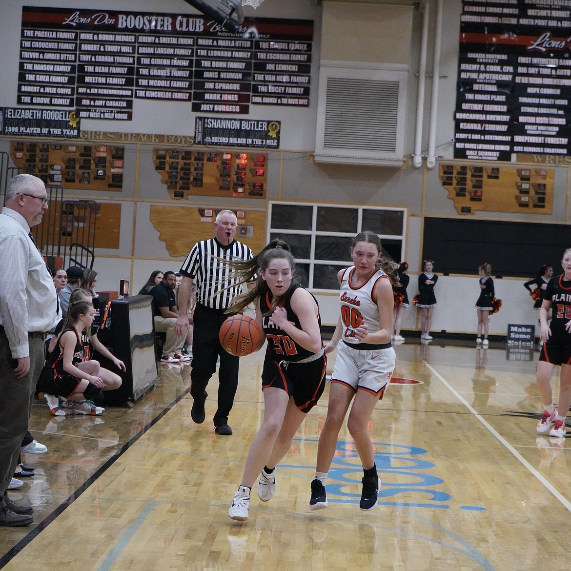 Plains Trotter Trystan Larson drives past a Eureka lady Lion under the watchful eye of coach Brooks Sanford (left) during their game this past week in Eureka.  (Courtesy photo)