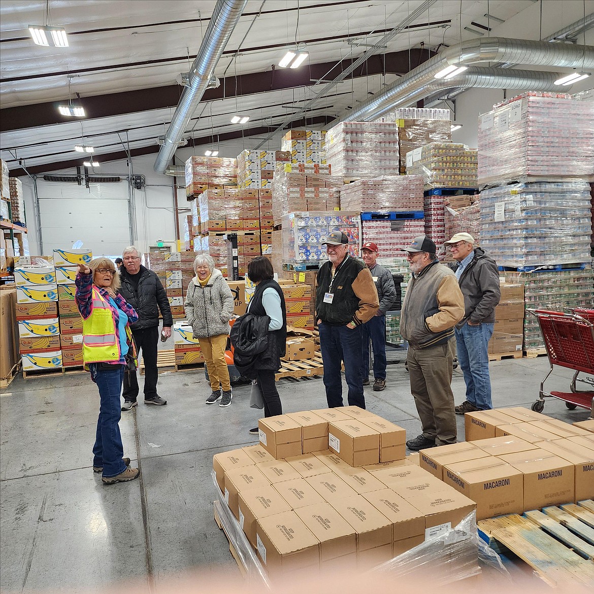 Members of the Moses Lake Classic Car Club get a tour of the food bank’s warehouse from Director Peny Archer, in yellow vest.