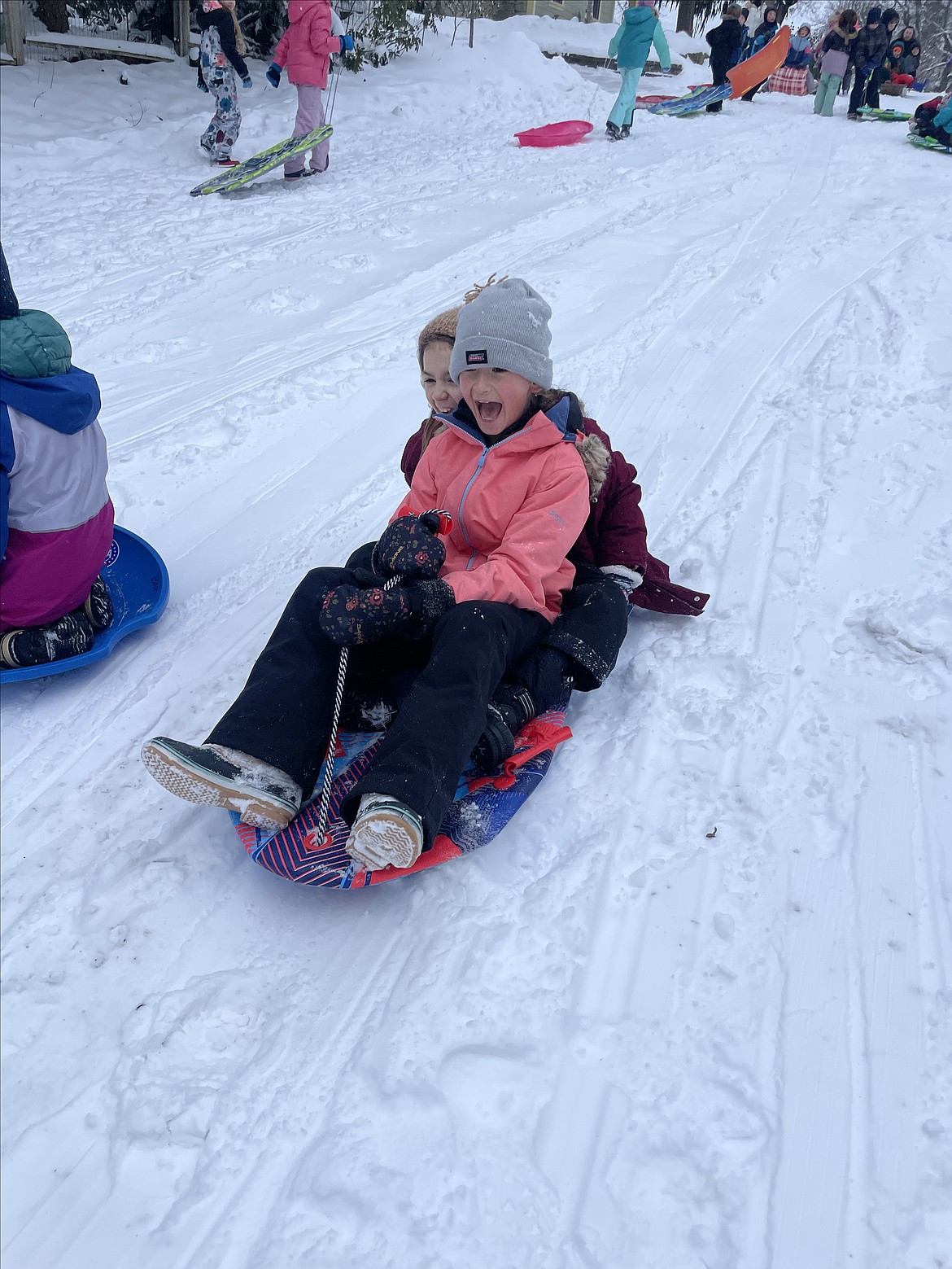 Third graders Audrey Rietz, front, and Savi Bousquet enjoy a trip down Boyd Hill during Sorensen Magnet School's Gaining Momentum sledding morning Friday in Coeur d'Alene.