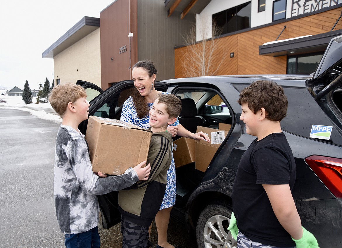 Rankin Elementary fifth-graders Blake Benkelman, Austin Parker and Armand Sieler help Amanda Curtis, president of the Montana Federation of Public Employees, carry boxes of books purchased for the school through a "Read Across America" grant from American Federation of Teachers on Tuesday, Jan. 24, 2024. (Photo by Hilary Matheson/Daily Inter Lake)