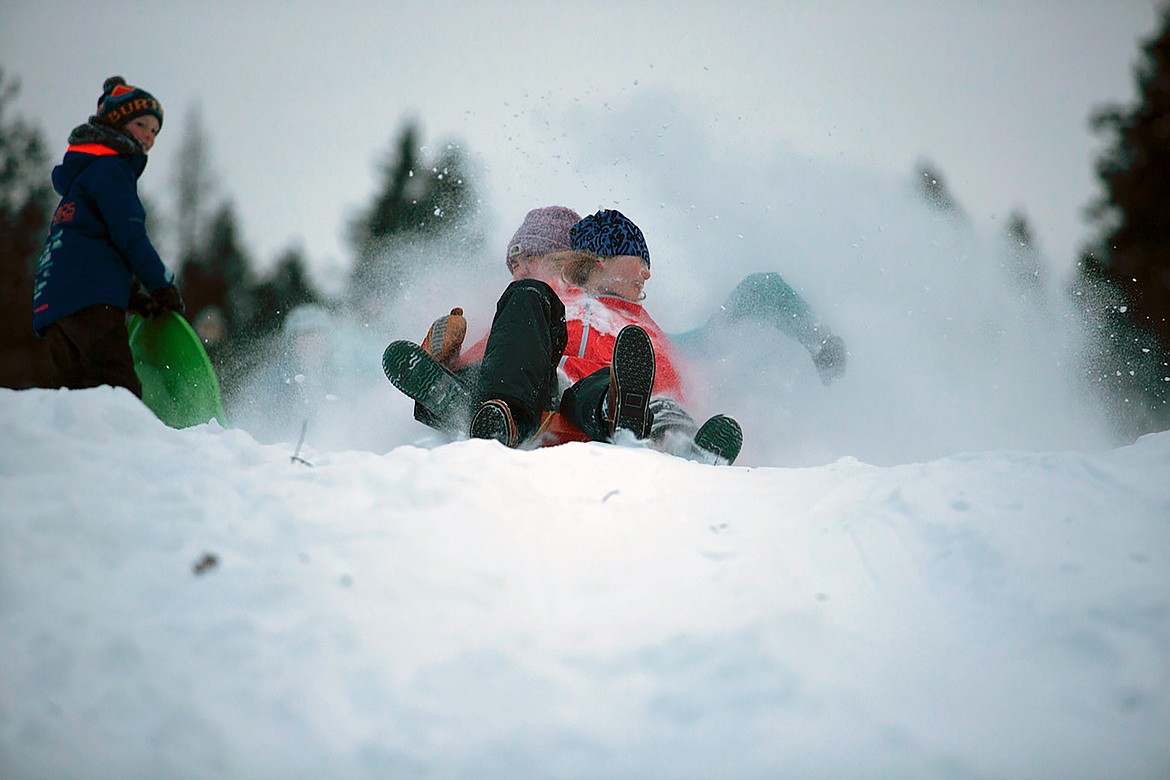 A pair of sledders are sprayed by snow and they fly down the Pine Street Sled Hill on Tuesday, Jan. 16. The sled hill has reopened after the Kaniksu Land Trust purchased the 48-acre site last year after a successful community fundraising campaign.