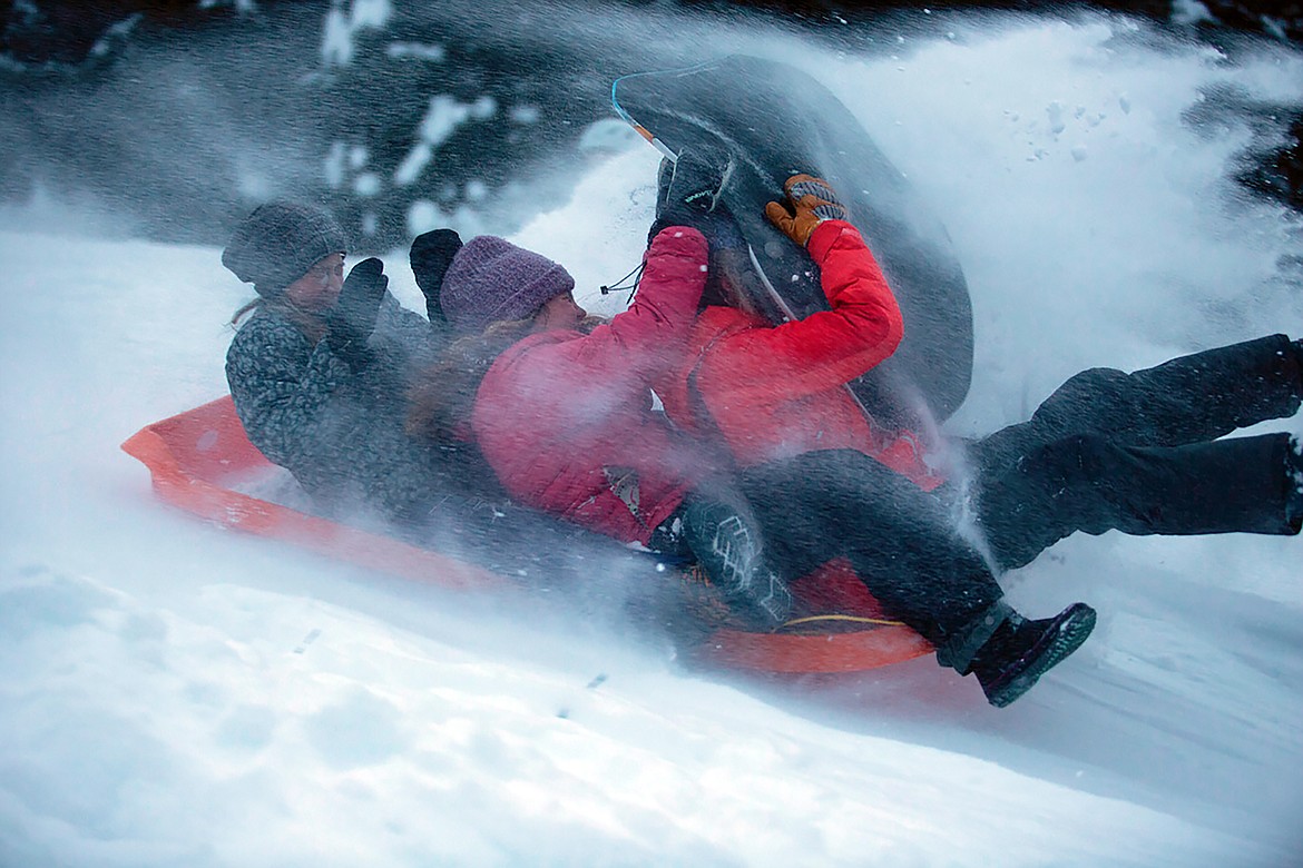 Sledders are sprayed by snow as they fly down the Pine Street Sled Hill on Tuesday, Jan. 16. The sled hill has reopened after the Kaniksu Land Trust purchased the 48-acre site last year after a successful community fundraising campaign.