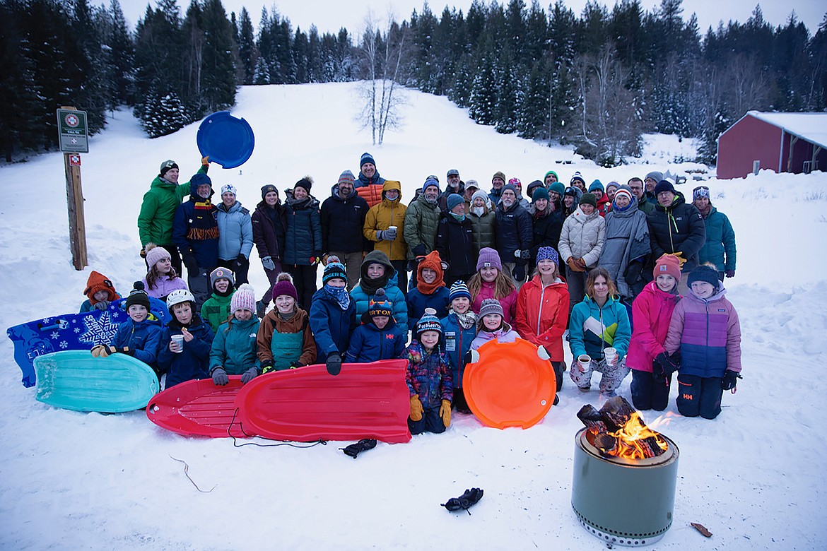 Sledders and community members gather for a group photo at the Pine Street Sled Hill on Tuesday, Jan. 16. The sled hill has reopened after the Kaniksu Land Trust purchased the 48-acre site last year after a successful community fundraising campaign.