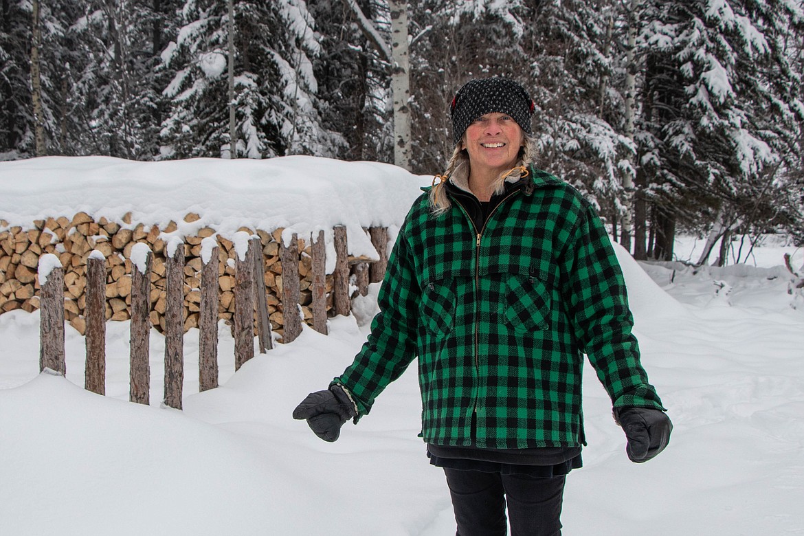 Pattiann Bennett, the leader of the St Michael & All Angels Wood Ministry in Fortine, stands next to a pile of wood on Jan. 20, 2024. (Kate Heston/Daily Inter Lake)