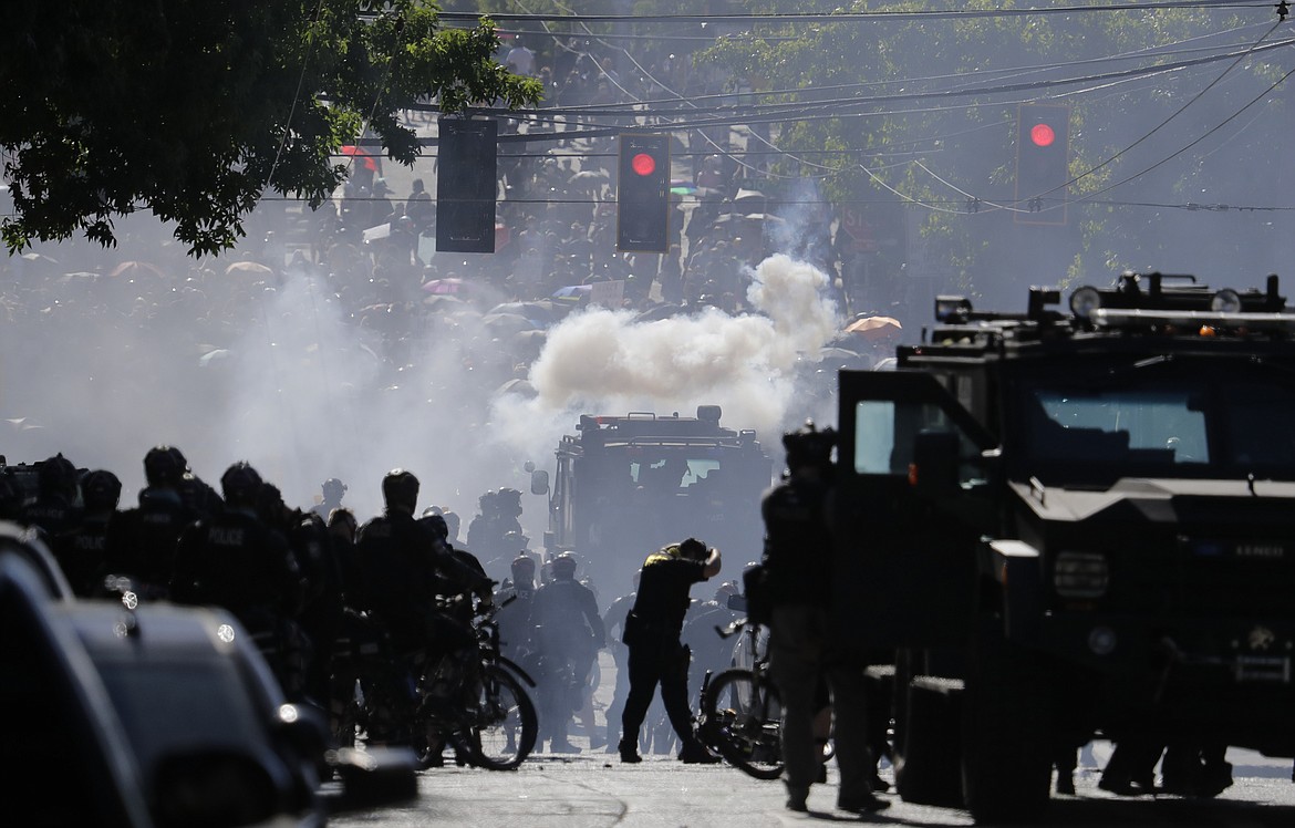 Smoke rises as police clash with protester during a Black Lives Matter protest near the Seattle Police East Precinct headquarters, July 25, 2020, in Seattle. Seattle has agreed to pay $10 million to 50 demonstrators who sued over the police department’s heavy-handed response to racial justice protests in 2020, attorneys for both sides said Wednesday, Jan. 24, 2024. (AP Photo/Ted S. Warren, File)