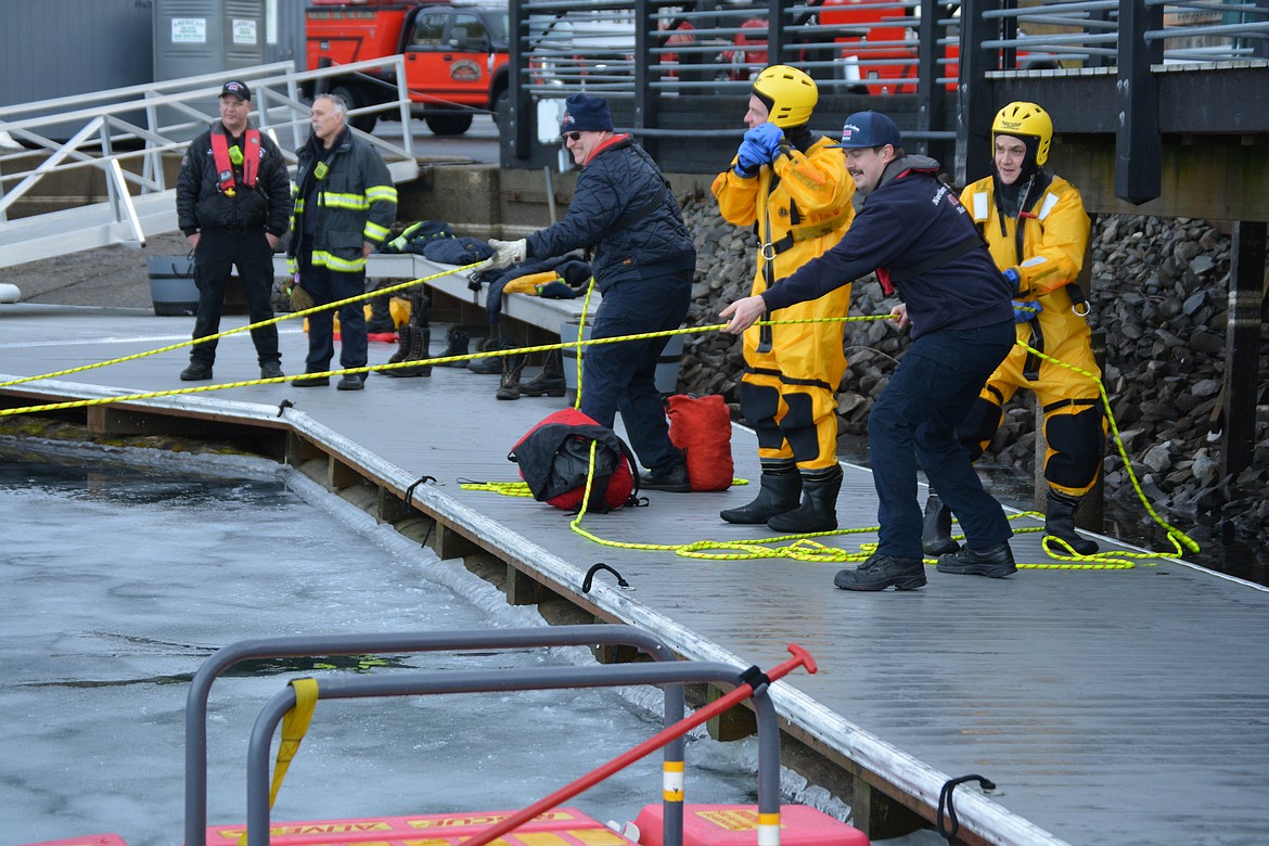 Brad Belmont and Jerry Moreau strategize for the next wave of ice rescue simulations as Chris Larson, Eric Steiger, and Dan Parrish haul Tyler Denham and Tyler Turrell to safety during a rescue simulation with Northern Lakes Fire. Behind Larson, Ryan Altus buckles his helmet.