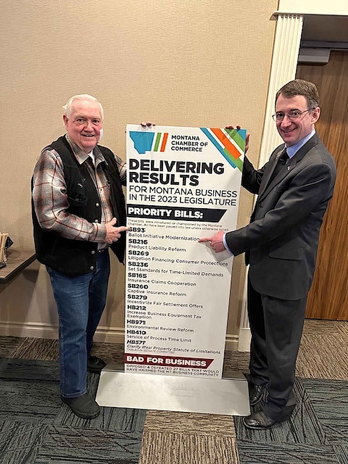 CHAMPION OF BUSINESS awards were presented recently to a number of Montana lawmakers, including Sen. Mike Cuffe (R-Lincoln County) at left. Pointing to SB 93 which Cuffe sponsored is Charles Robison, Montana Chamber of Commerce director of political affairs. (Courtesy photo)