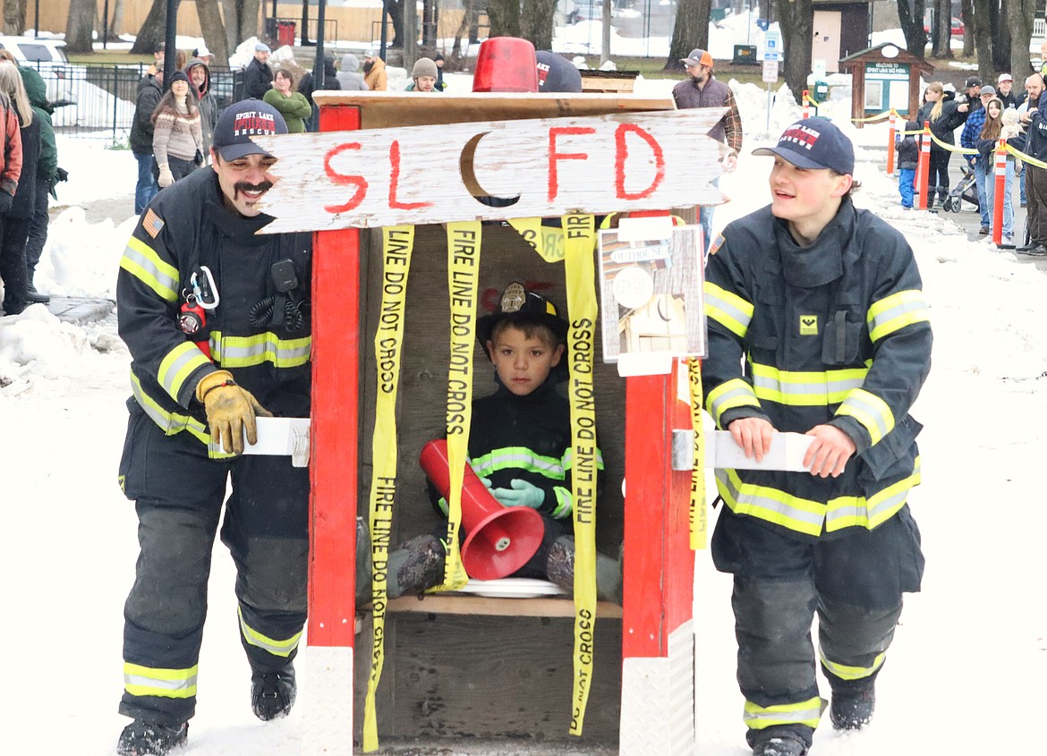 Spirit Lake firefighter Taten Novak, right, and Bryan Sexton push their outhouse toward the starting line on Saturday.