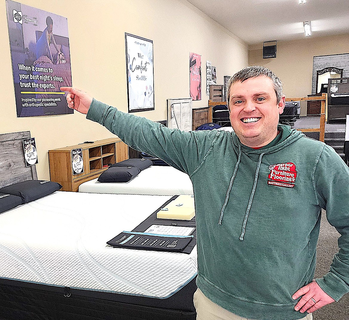 Rocky Whisman, Jr., points out a Sealy sign in the Mattress Gallery at Harbor Light Furniture and Flooring. (Berl tiskus/Leader)