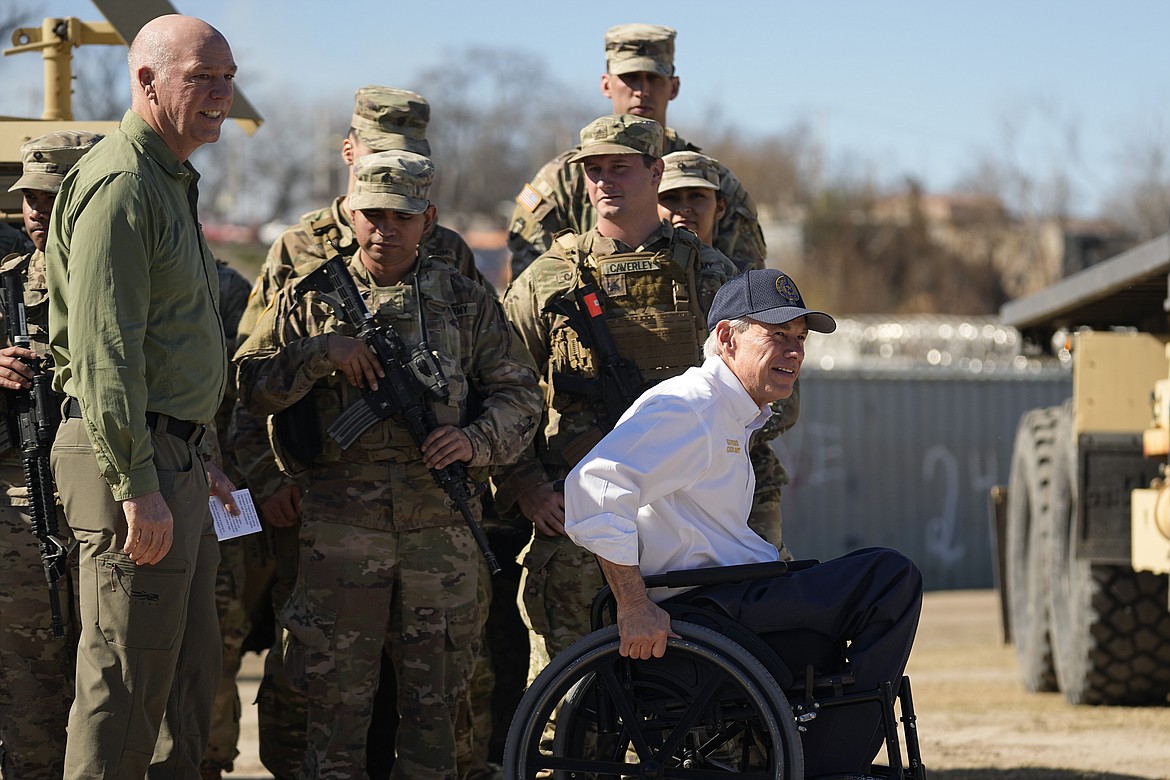 Texas Gov. Greg Abbott, right, and Montana Gov. Greg Gianforte, left, walk past members of the National Guard as they arrive with fellow governors for a news conference along the Rio Grande to discuss Operation Lone Star and border concerns, Sunday, Feb. 4, 2024, in Eagle Pass, Texas. (AP Photo/Eric Gay)