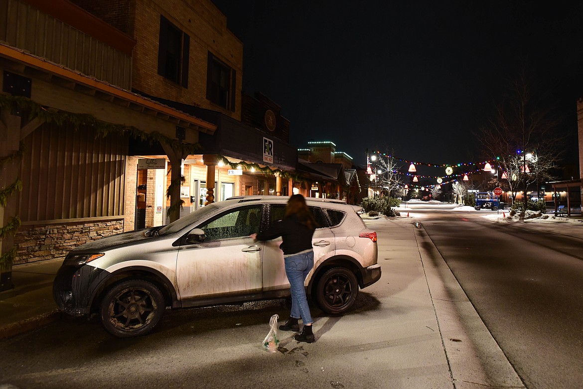 Carli Dewbre, with the Montana Bar Fairies, places a coffee card, thanking people for not drinking and driving, onto a car in Whitefish that was possibly left overnight. Dewbre's brother, Bobby, was struck and killed by a drunk driver last year. (Kate Heston/Daily Inter Lake)